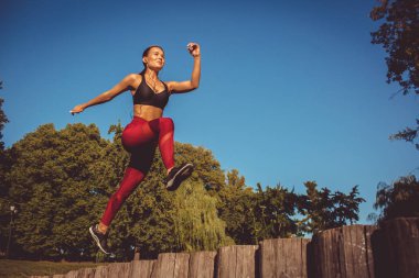 kadın kırmızı tozluk ve koşma ve atlama park, düşük açılı görünüş sportif üst