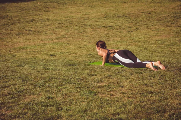 barefoot woman practicing yoga in park on green grass meadow, Lying Down Yoga Asanas