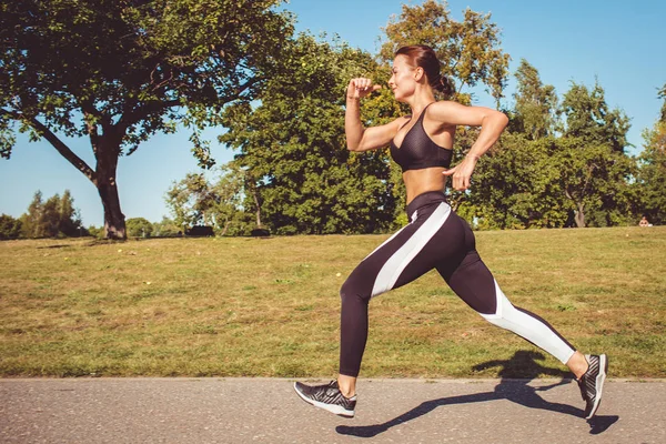 beautiful woman in black white leggings and sportive top running in park