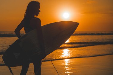 sörfçü kadın silueti günbatımında poz denizde surfboard ile yan görünüm