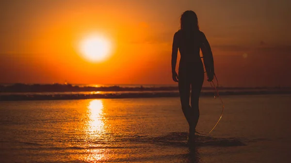 海でサーフボードを持つサーファー女性の背面図 — ストック写真