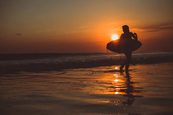 surfer woman  with surfboard in ocean water enjoying sunset