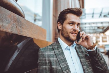 yakışıklı beyaz işadamı duran binasında cep telefonunda konuşuyor 