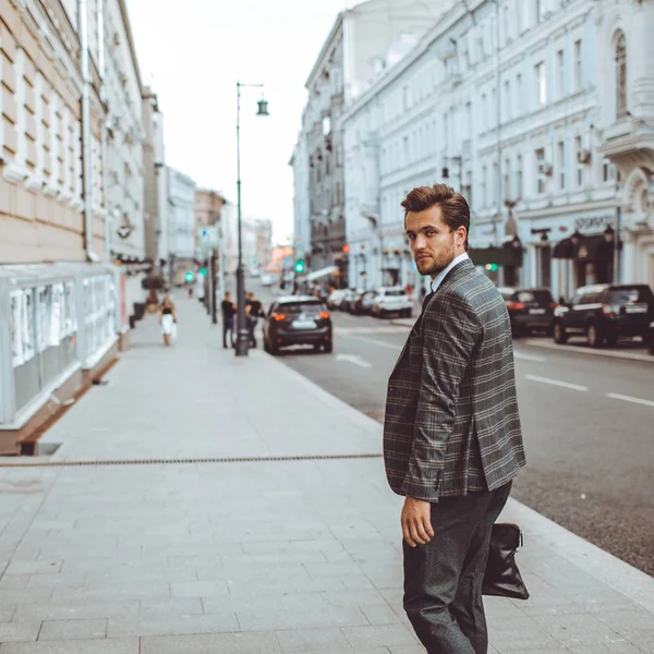 stylish Caucasian gentleman in tweed suit jacket walking in street at road with cars