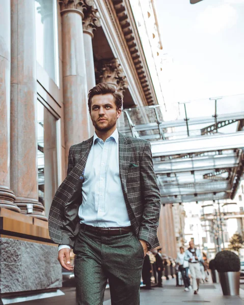 serious elegant Caucasian gentleman in tweed suit jacket walking in street at building