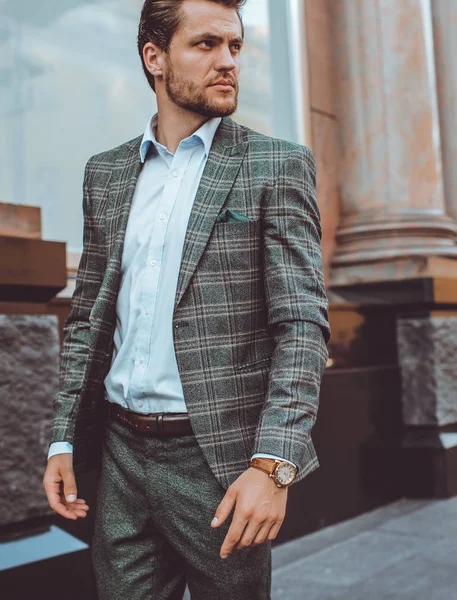 handsome Caucasian businessman in tweed suit jacket outdoors at hotel building