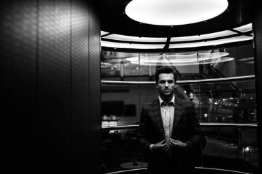 tüvit takım elbise ceket ayarlama ve cam Asansör içinde duran yakışıklı beyaz beyefendi 