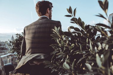 arkadan görünüşü tesisinde çatıda oturan tüvit ceketli adamı 