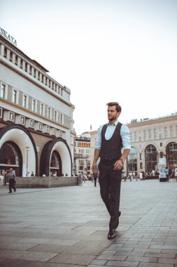 Şehir caddede yürüyüş takımı yelek şık yakışıklı beyaz adamın tam uzunlukta