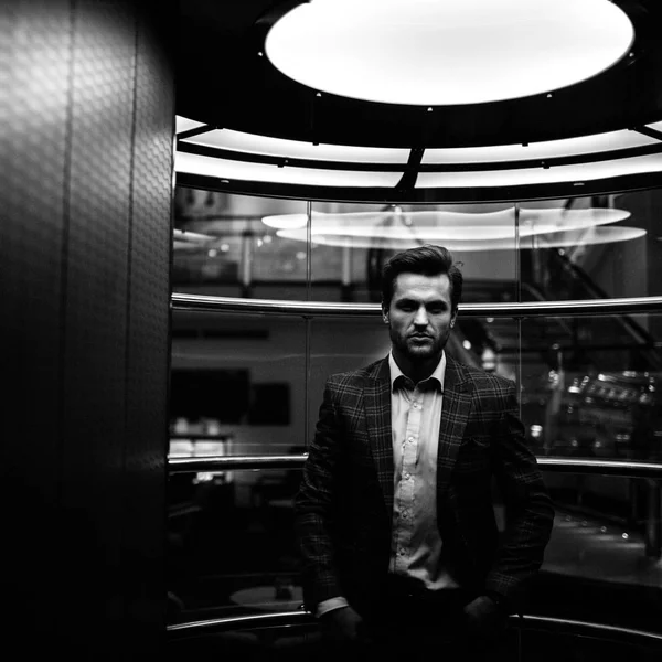 handsome Caucasian gentleman in tweed suit jacket and posing in glass elevator