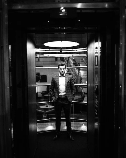 gentleman in tweed suit jacket standing in glass elevator
