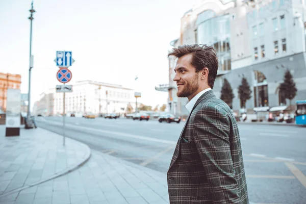 smiling stylish Caucasian gentleman in tweed suit jacket walking in street at road with cars