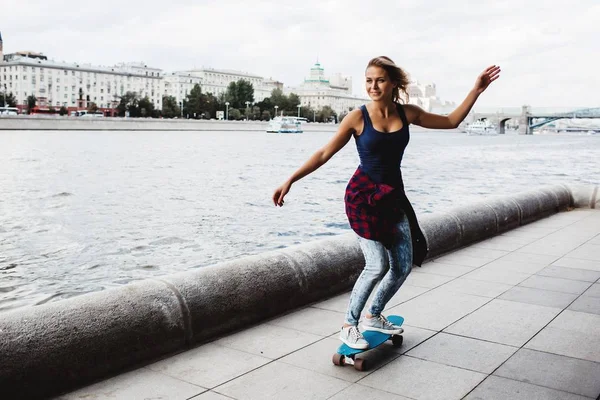 full length of blonde woman riding on skateboard at river