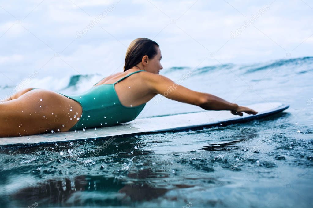 beautiful girl surfer swims on a board in the indian ocean on bali island