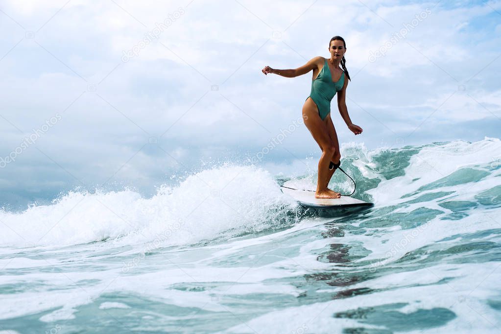 beautiful surfer girl riding on a board in the ocean on bali island