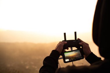 Gün batımında Batur yanardağında insansız hava aracını kontrol eden adam görüntüsü. Bali, Endonezya
