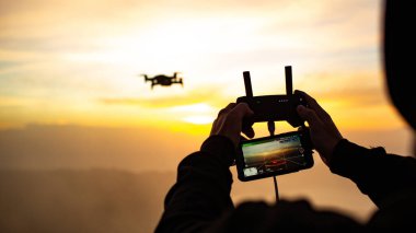 Gün batımında Batur volkanında insansız hava aracını kontrol eden adamın yakın görüntüsü. Bali, Endonezya