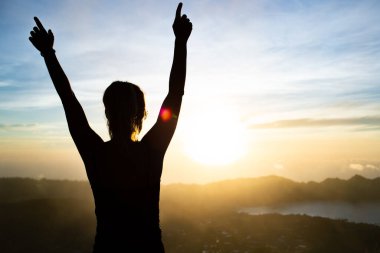 Endonezya, Bali 'de günbatımında poz veren güzel genç bir kadının silueti.