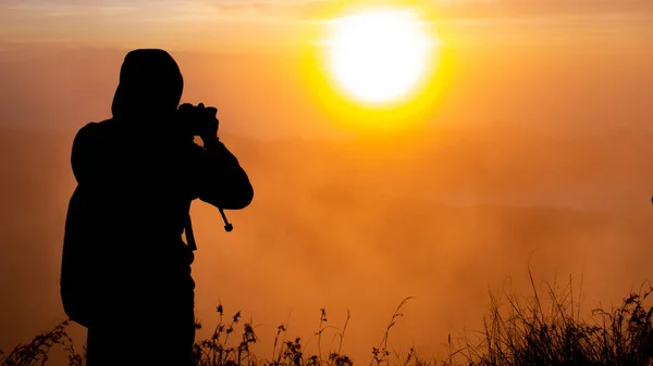 silhouette of photographer photographing dawn of the sun on the volcano Batur, Bali, Indonesia