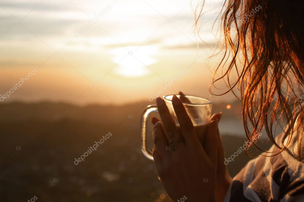 close-up view of girl drinking coffee at dawn on the volcano Batur, Bali, Indonesia