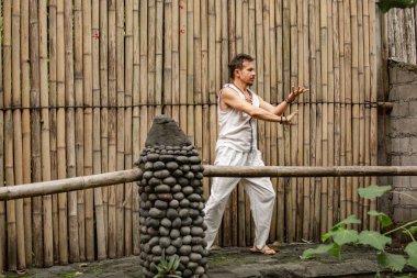 Şaman şelalenin yukarısındaki köprüde vücut egzersizleri yapıyor.