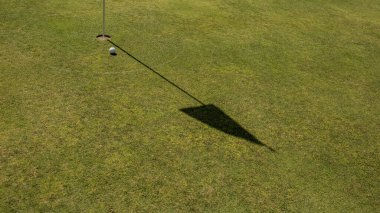 Yeşil çimlerin üzerinde bayrak direği ve top olan golf deliğine yakın çekim. Bali. Endonezya.