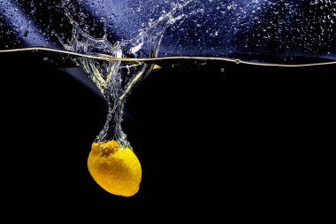 Açık şeffaf suda süzülen olgun sarı limon manzarası.