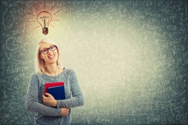 Gözlük takan ve tahta arka plan ile baş, yukarıda bir ampul kroki üzerinde iki kitap ayakta tutan genç kadın çözme matematiksel denklemler, hesaplama ve formüller sofistike.