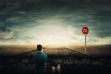 Bir adam olarak gerçeküstü görünümü standı ezici bir asfalt yol ve bir kırmızı dur işareti önünde. Derin çukur, uçurum işadamı için kırık yolu olarak. Kariyer zorluklar ve üstesinden gelmek için başarı elde.