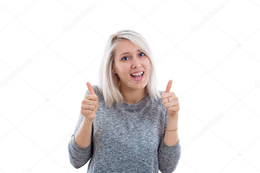 Portrait of a cheerful blonde woman showing thumbs up. Girl in casual clothes looking at camera with joyful and charming smile. Copy space, white background.