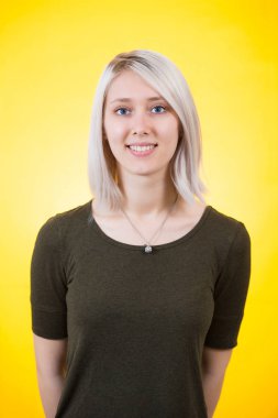 Neşeli genç kadın elle onun arkasından sarı renkli arka plan üzerinde izole kamera için arıyor.