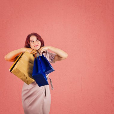 Genç Kızıl saçlı kadın altında el ile taşıma alışveriş torbaları mutlu ararken çene ve üzerinde kırmızı arka plan kopya alanı ile izole meditasyon.