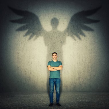 Casual confident man arms crossed. Full length portrait casting a superhero shadow with angel wings on a dark room wall. Inner power, ambition and leadership concept. clipart