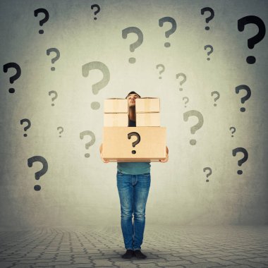 Tam uzunlukta soru işaretleri kutularıyla yığını arkasında gizli ağır paketleri taşıyan karışık genç adam portresi. Bilinmeyen paket kimliğini gizleme kurye.
