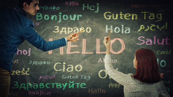 Man and woman together drawing word hello in different languages and colors on blackboard. Opportunity for learning many languages for students. Business partnership and teamwork concept.