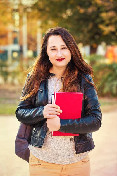 在她的手上大学的背包和书籍的年轻妇女学生的户外肖像 — 图库照片