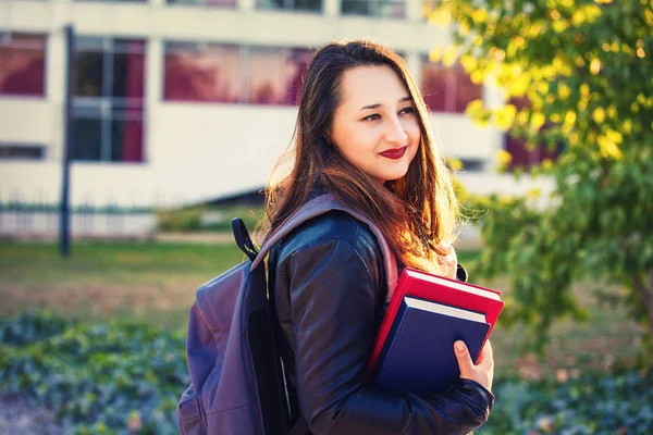 沉思的年轻女子学生携带背包和持有书籍去大学 — 图库照片