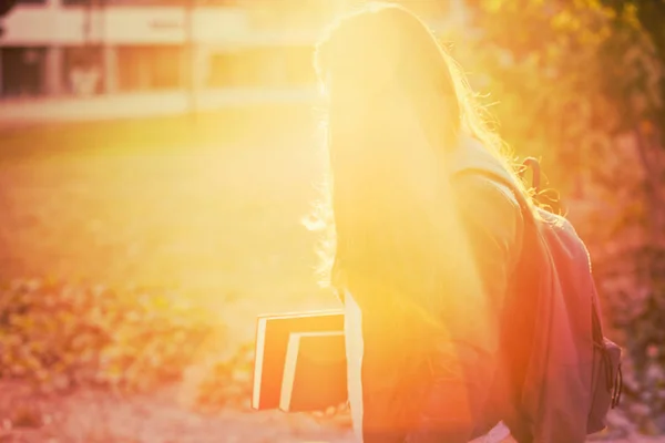 バックパックと書籍 太陽を運ぶ若い学生女性のシルエット線穏やかで 穏やかなオレンジの効果 — ストック写真