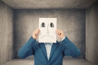Yüzünü bir beyaz kağıt ile çizilmiş üzgün ifadeyi kullanarak kapsayan iş adamı, onun gerçek duygular bir dolap odada toplumdan gizleme için sahte bir maske gibi kroki. İzole gri duvar arka plan.