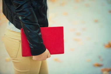 Açık havada bakış kopya alanı ile bir kırmızı kitap tutan kadın öğrenci el kapatın