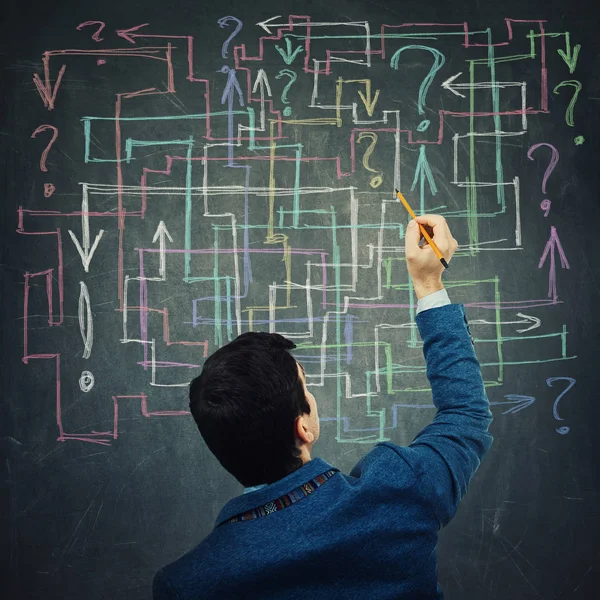 Rear view of a young businessman drawing different colorful arrows try to solve a questions maze and find the answer. Problem analysis solution concept.