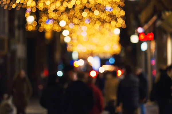 Blur background of crowd on city street decorated with christmas lights.