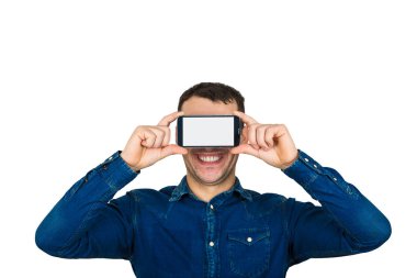 Mutlu genç adam öğrenci Smartphone sanal gerçeklik gözlüklerle bakmak hoşuna gidiyor gözler yakın tutan mavi ceket giyiyor. Yeni teknoloji üretimi ile eğleniyor mani eğilimleri üzerine beyaz izole.