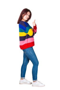 Yan görünümü tam uzunlukta up kamera gülümseyen için seyir başparmak tutan genç ve güzel kadın portresi. Casual kız mutlu duygu beyaz arka plan üzerinde izole jest sembolü gibi gösterilen.