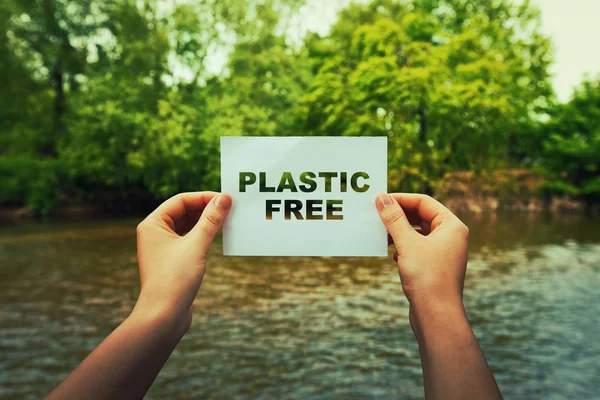 妇女手拿着一张纸与塑料自由文本在自然的中间在流动的河和绿色森林附近 生态概念 回收符号 无塑料区 — 图库照片