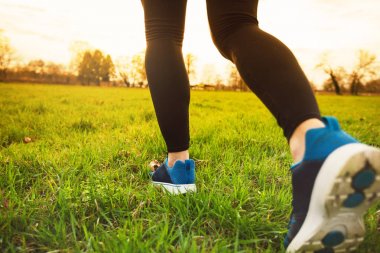 Koşucu atlet ayakları çim üzerinde çalışıyor. Erkek Fitness güneş ışığı jogging egzersiz. Spor atlet aktif yaşam tarzı kavramı. Günbatımı Şehir Parkı sırasında çim üzerinde çalışan bacaklar atletik çifti.