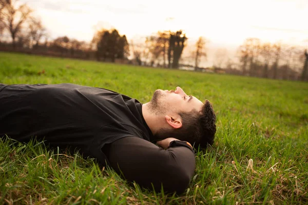Athlete resting relaxing lying on grass — Stock Photo, Image