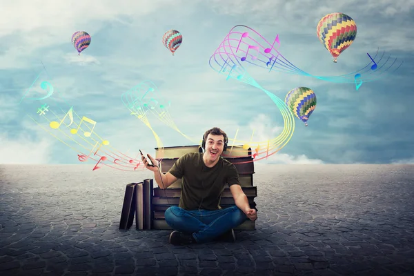 Joyful student guy seated relaxed on the floor listening to a so — Stock Photo, Image