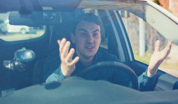 Hombre enojado conduciendo un vehículo discutiendo y haciendo gestos agitando su ha —  Fotos de Stock