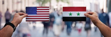 İki el farklı bayraklar tutarken, ABD-Suriye arasında siyaset
